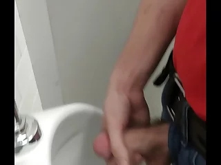 A daring office worker indulges in self-pleasure, discretely stroking himself and releasing his climax into the urinal. The thrill of the risk and the satisfaction of his solo act make it a tantalizing spectacle.